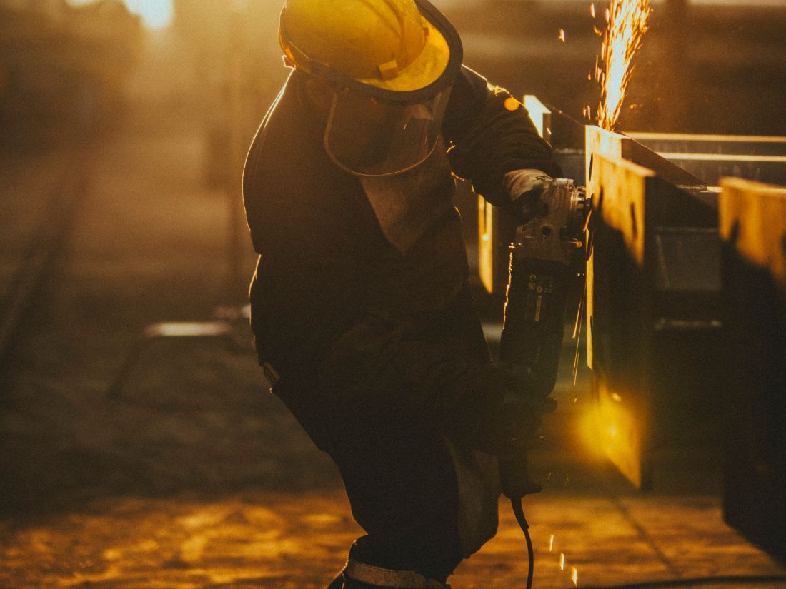 Tradesperson grinding steel with sparks at an industrial facility